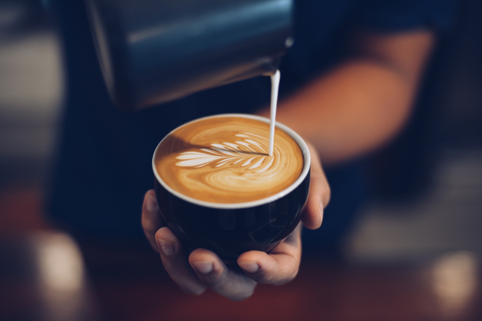 Barista pouring latte art into a cup